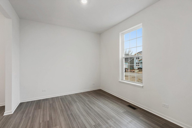 unfurnished room featuring dark wood-style floors, visible vents, and baseboards