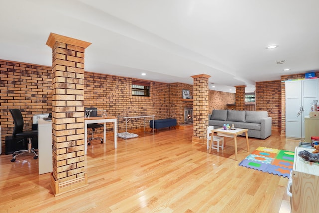 living room with recessed lighting, wood finished floors, brick wall, and ornate columns