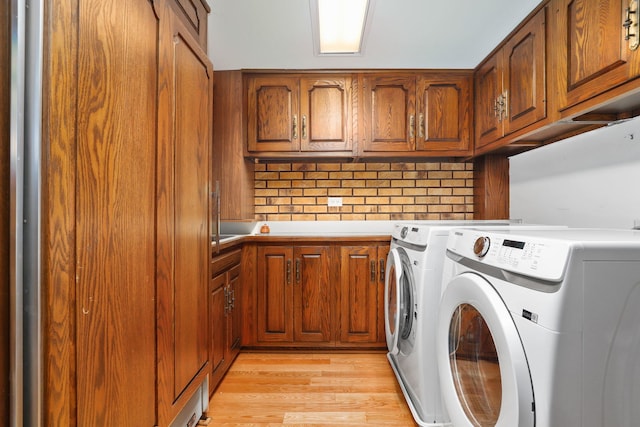 clothes washing area with cabinet space, independent washer and dryer, and light wood finished floors