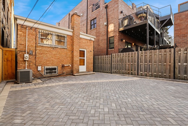 back of property featuring central air condition unit, fence, and brick siding