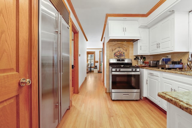 kitchen with decorative backsplash, light wood-style floors, appliances with stainless steel finishes, and white cabinetry