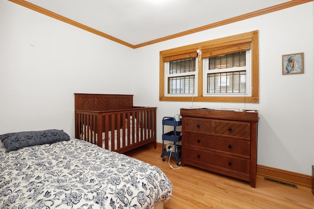 bedroom featuring visible vents, crown molding, baseboards, and wood finished floors