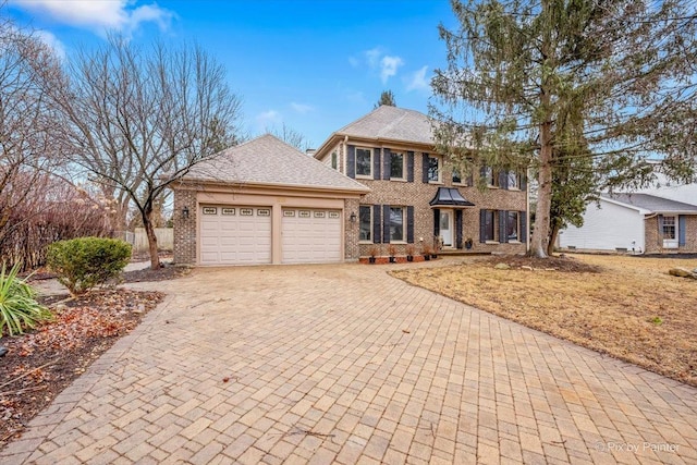 colonial inspired home with a garage, decorative driveway, and brick siding