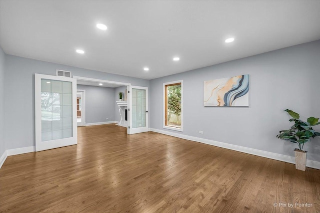 unfurnished living room featuring visible vents, baseboards, wood finished floors, and a fireplace