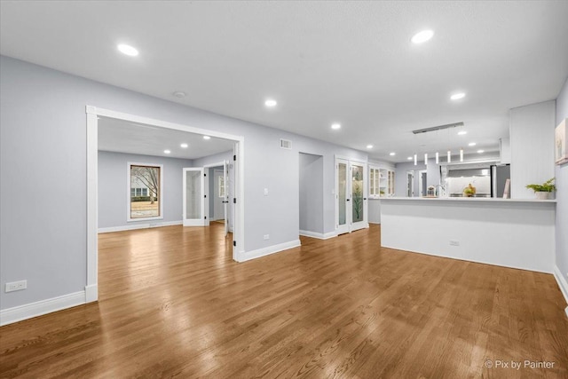 unfurnished living room featuring recessed lighting, wood finished floors, visible vents, and baseboards