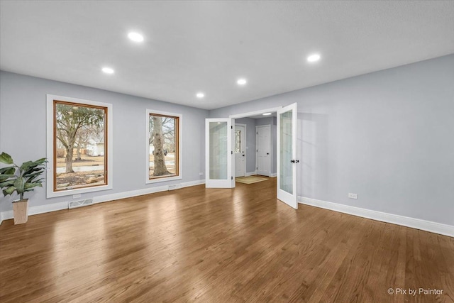 unfurnished living room with wood finished floors, french doors, visible vents, and baseboards