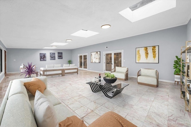 living area with french doors, baseboards, marble finish floor, and a skylight