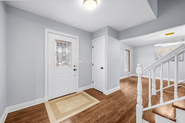 foyer with dark wood finished floors, stairway, plenty of natural light, and baseboards