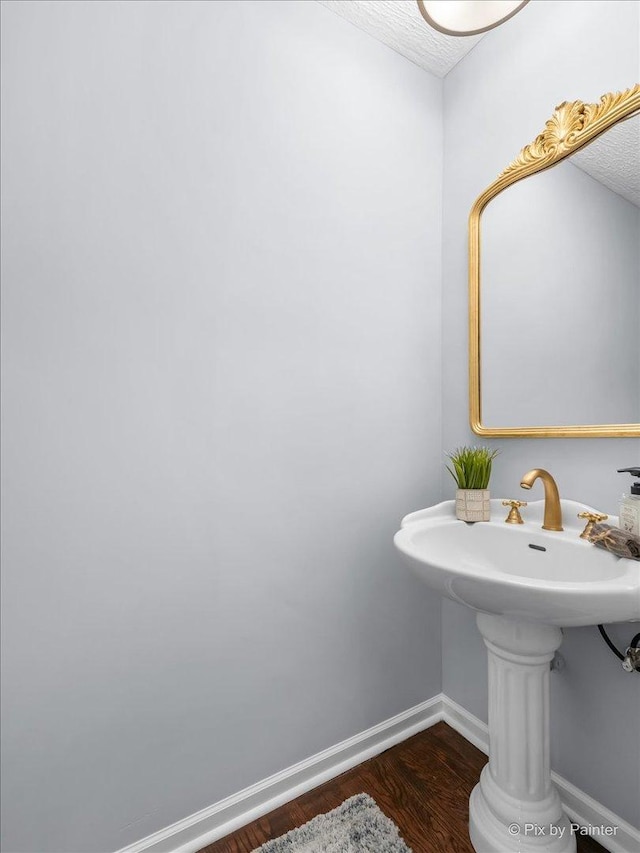 bathroom featuring baseboards, a textured ceiling, and wood finished floors