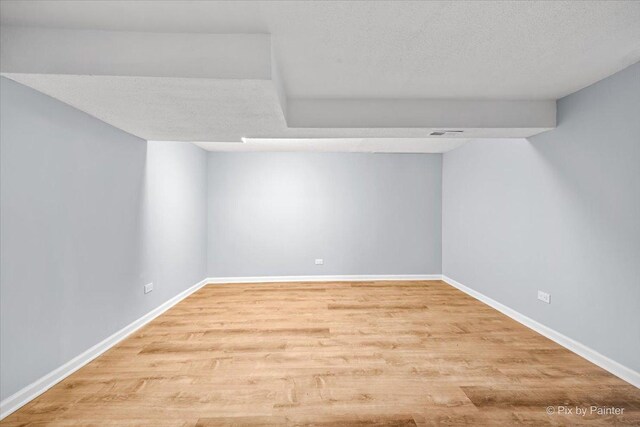 interior space with visible vents, a textured ceiling, baseboards, and wood finished floors