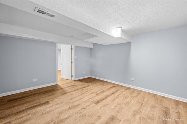 finished basement featuring visible vents, baseboards, a textured ceiling, and wood finished floors