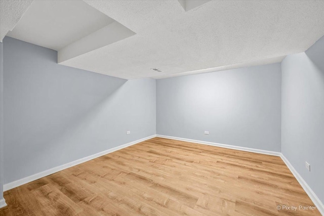 additional living space featuring visible vents, wood finished floors, baseboards, and a textured ceiling