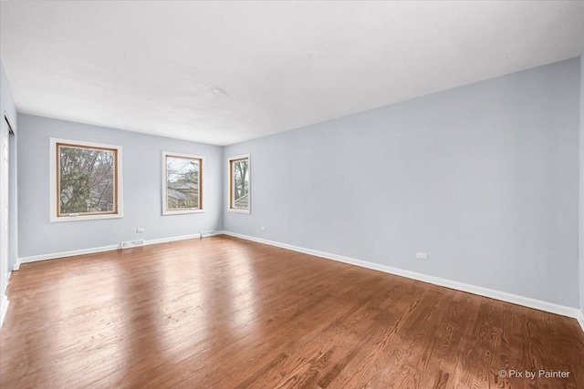 unfurnished room featuring wood finished floors, visible vents, and baseboards