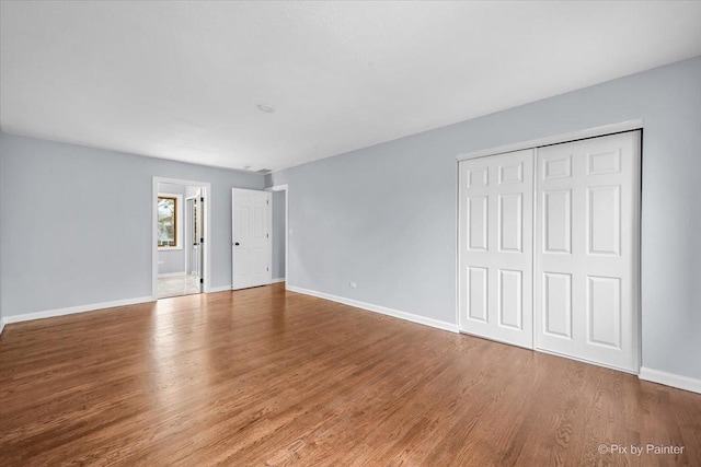 unfurnished bedroom with a closet, baseboards, and wood finished floors