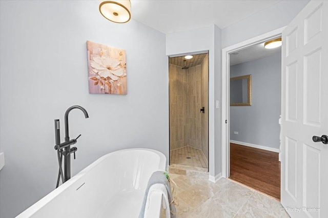 full bathroom with baseboards, a stall shower, and a freestanding bath