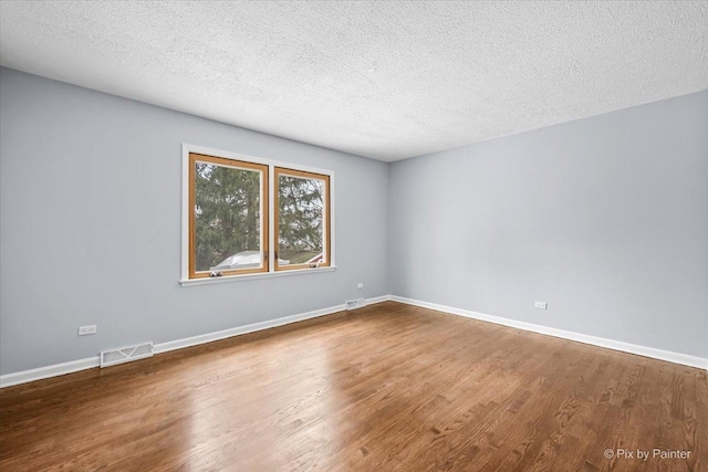 empty room with visible vents, baseboards, and wood finished floors