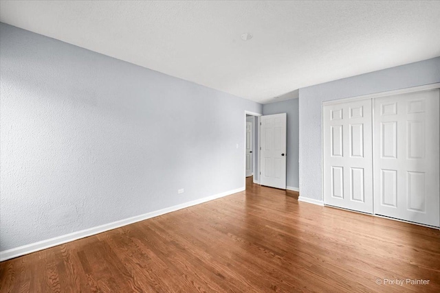 unfurnished bedroom featuring a closet, baseboards, and wood finished floors