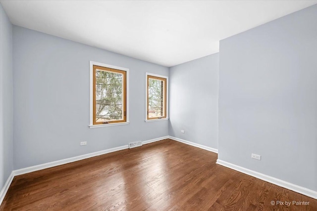 spare room with dark wood-type flooring, baseboards, and visible vents