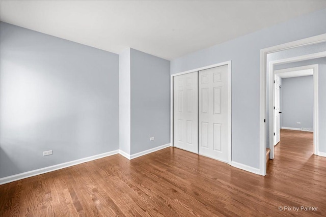 unfurnished bedroom with a closet, baseboards, and wood finished floors