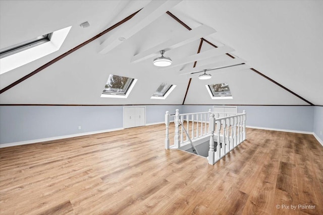 additional living space featuring lofted ceiling with skylight, ceiling fan, baseboards, and wood finished floors