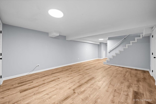 finished basement featuring stairway, baseboards, and wood finished floors