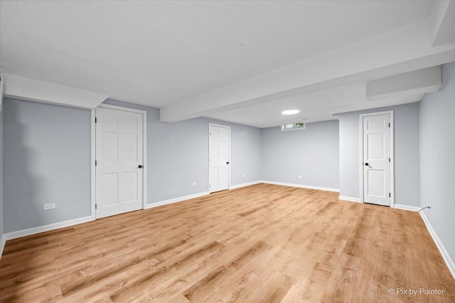 finished basement with baseboards and light wood-type flooring