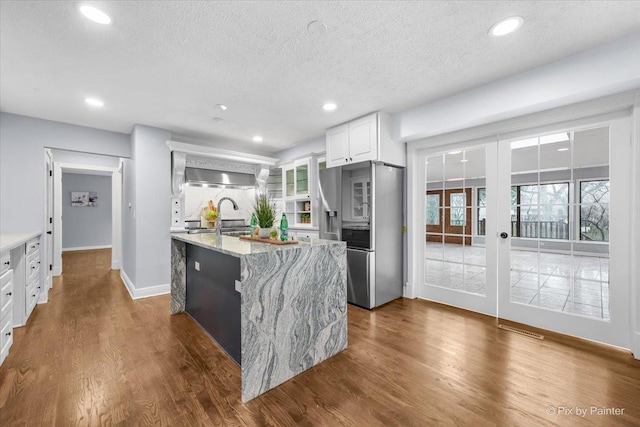 kitchen featuring dark wood-type flooring, white cabinetry, french doors, stainless steel fridge, and light stone countertops