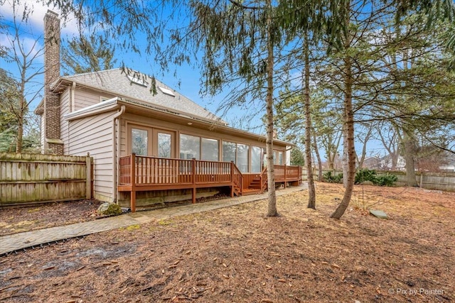 rear view of property with a wooden deck, a shingled roof, and fence