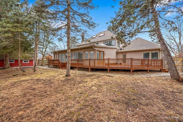 back of property featuring fence, a shed, a wooden deck, a chimney, and an outdoor structure