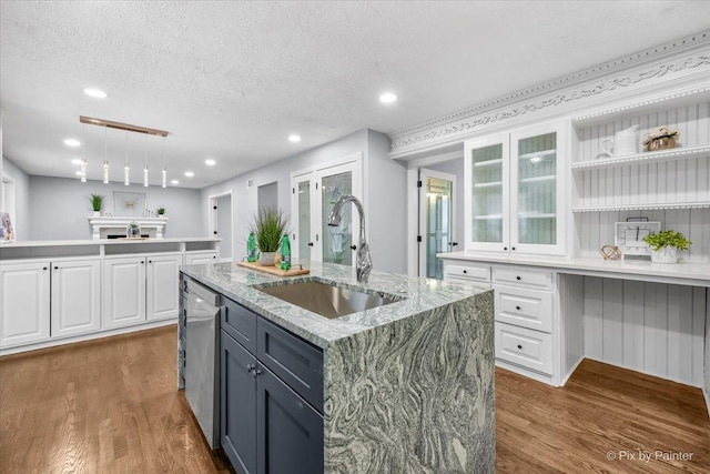 kitchen featuring wood finished floors, dishwasher, white cabinetry, and a sink