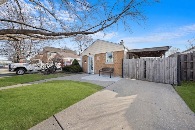 view of front of house featuring brick siding, a chimney, a front lawn, and fence