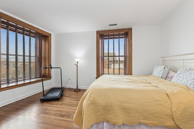 bedroom with visible vents, baseboards, and wood finished floors