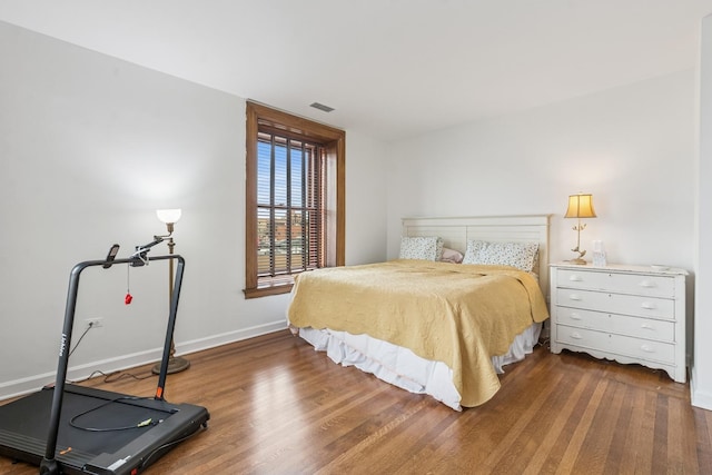 bedroom with visible vents, baseboards, and wood finished floors