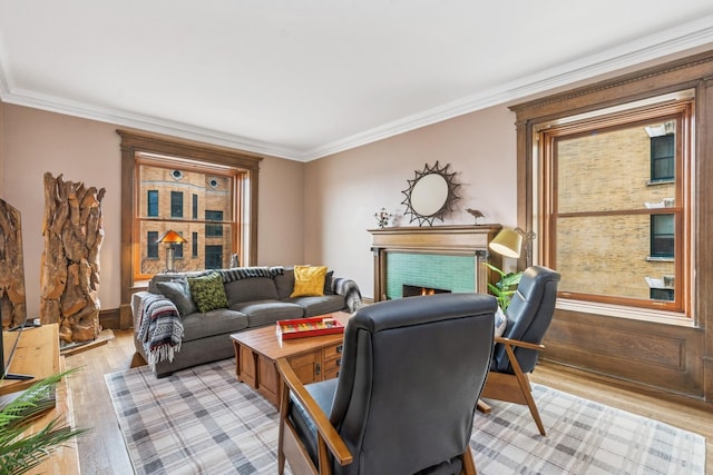 living area with a tiled fireplace, light wood-type flooring, and ornamental molding