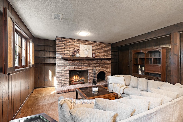 carpeted living room with wooden walls, a fireplace, a textured ceiling, and visible vents