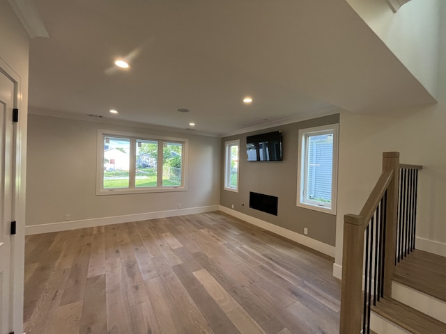 unfurnished living room featuring baseboards, light wood-style floors, and ornamental molding