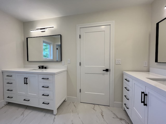 bathroom with marble finish floor, baseboards, and two vanities