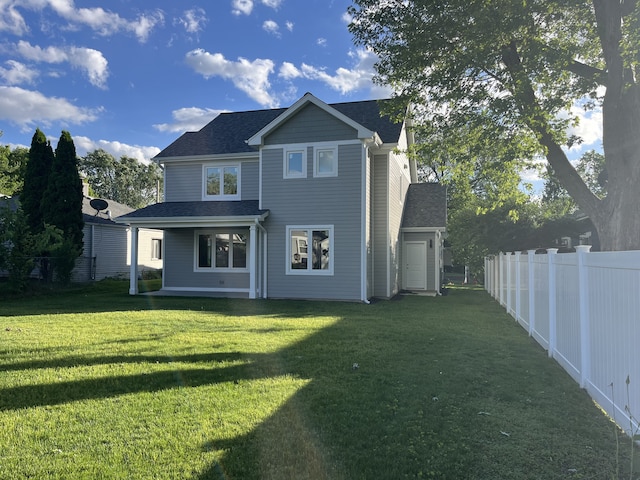 rear view of house with a yard, fence private yard, and a shingled roof