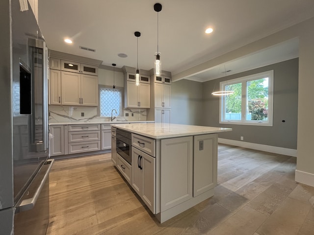 kitchen with visible vents, backsplash, a kitchen island, baseboards, and stainless steel appliances