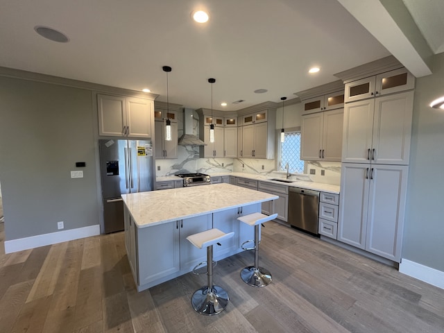 kitchen featuring a sink, decorative backsplash, stainless steel appliances, wall chimney range hood, and a center island