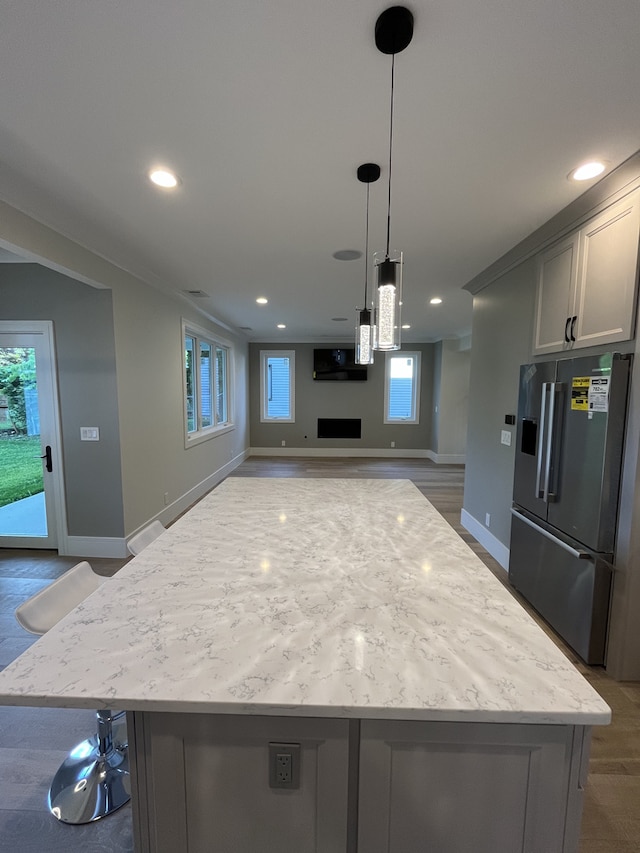 kitchen featuring recessed lighting, high end fridge, decorative light fixtures, open floor plan, and a center island