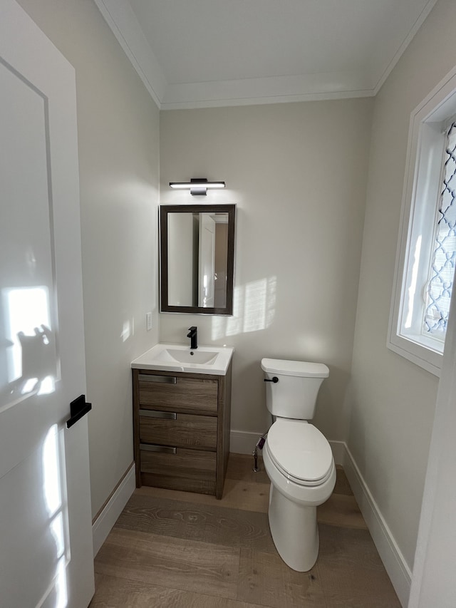 bathroom with vanity, crown molding, toilet, and wood finished floors