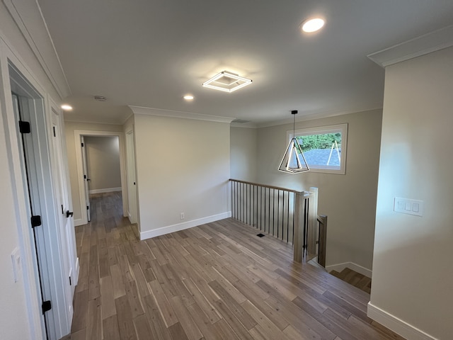 hallway featuring an upstairs landing, ornamental molding, baseboards, and wood finished floors