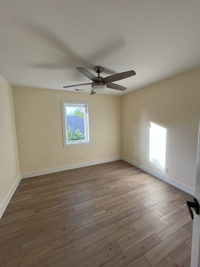 empty room featuring visible vents, ceiling fan, baseboards, and wood finished floors