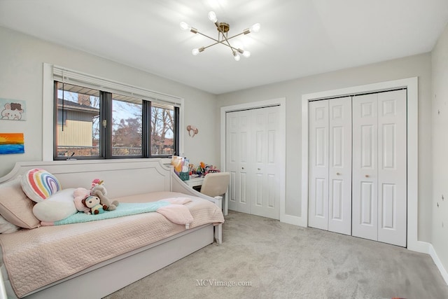 bedroom featuring a chandelier, light colored carpet, baseboards, and multiple closets