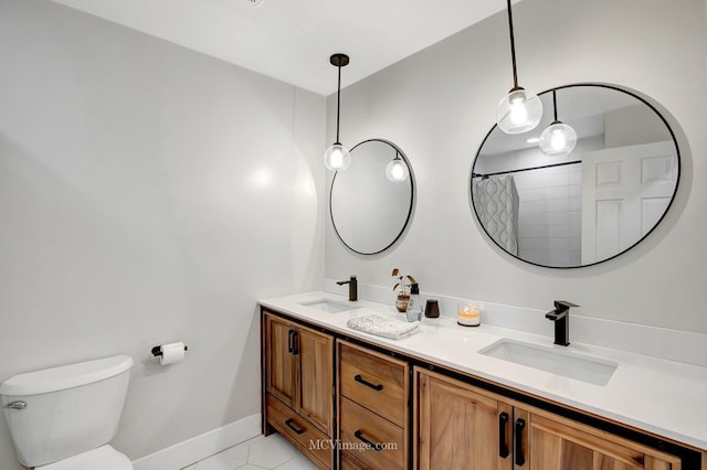 bathroom with double vanity, toilet, baseboards, and a sink