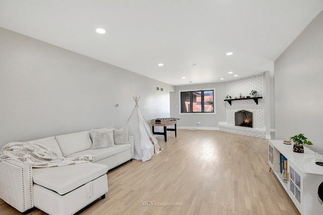 living area with visible vents, recessed lighting, a brick fireplace, and light wood-style floors