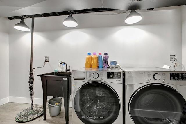 laundry area featuring washing machine and clothes dryer, laundry area, light wood-type flooring, and baseboards