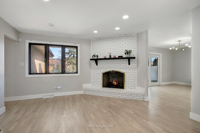 unfurnished living room featuring wood finished floors, visible vents, baseboards, recessed lighting, and a brick fireplace