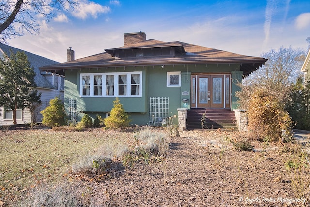 view of front of house with stucco siding, french doors, and a chimney